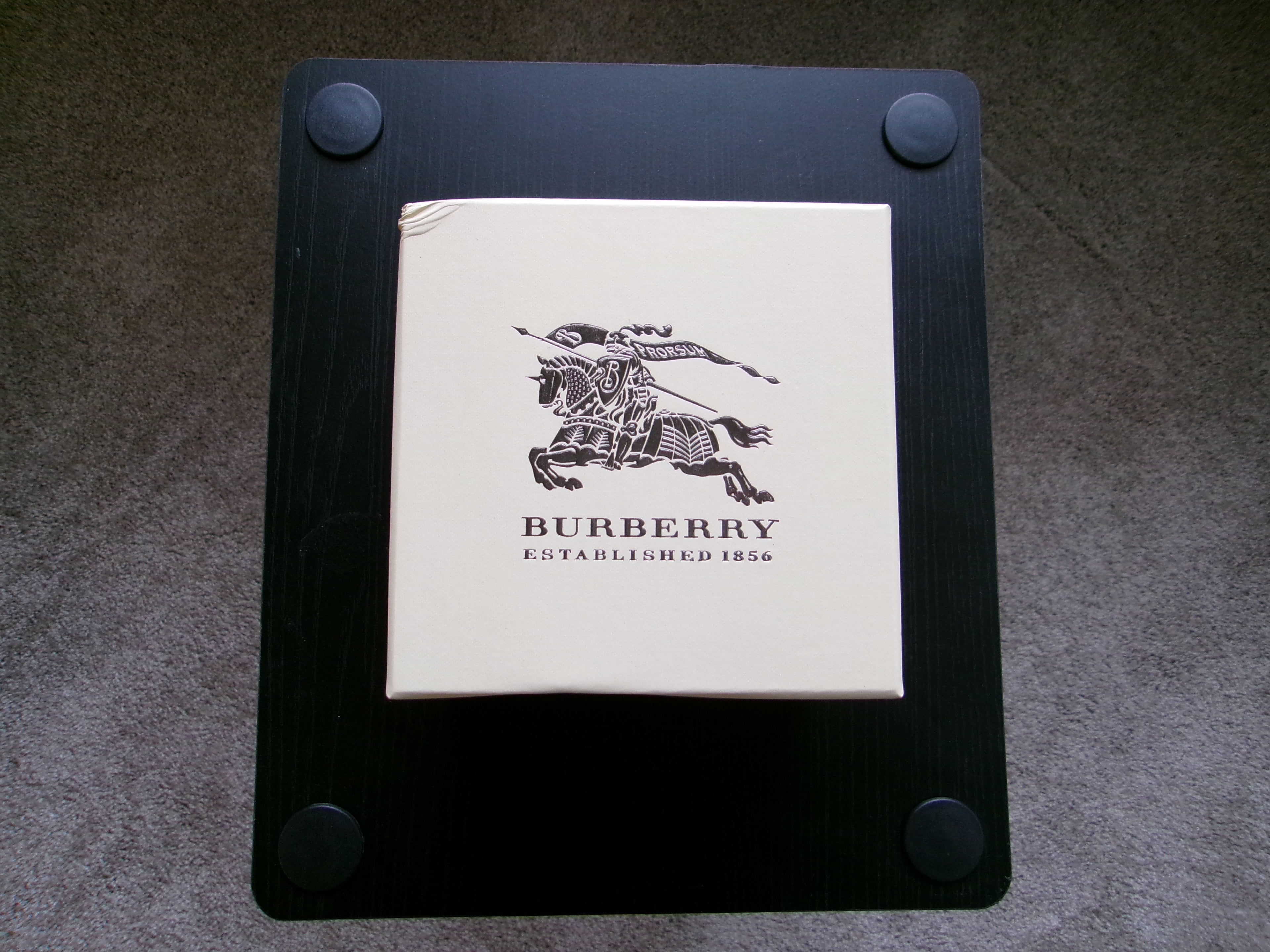 Burberry product on a black stand with a gray background