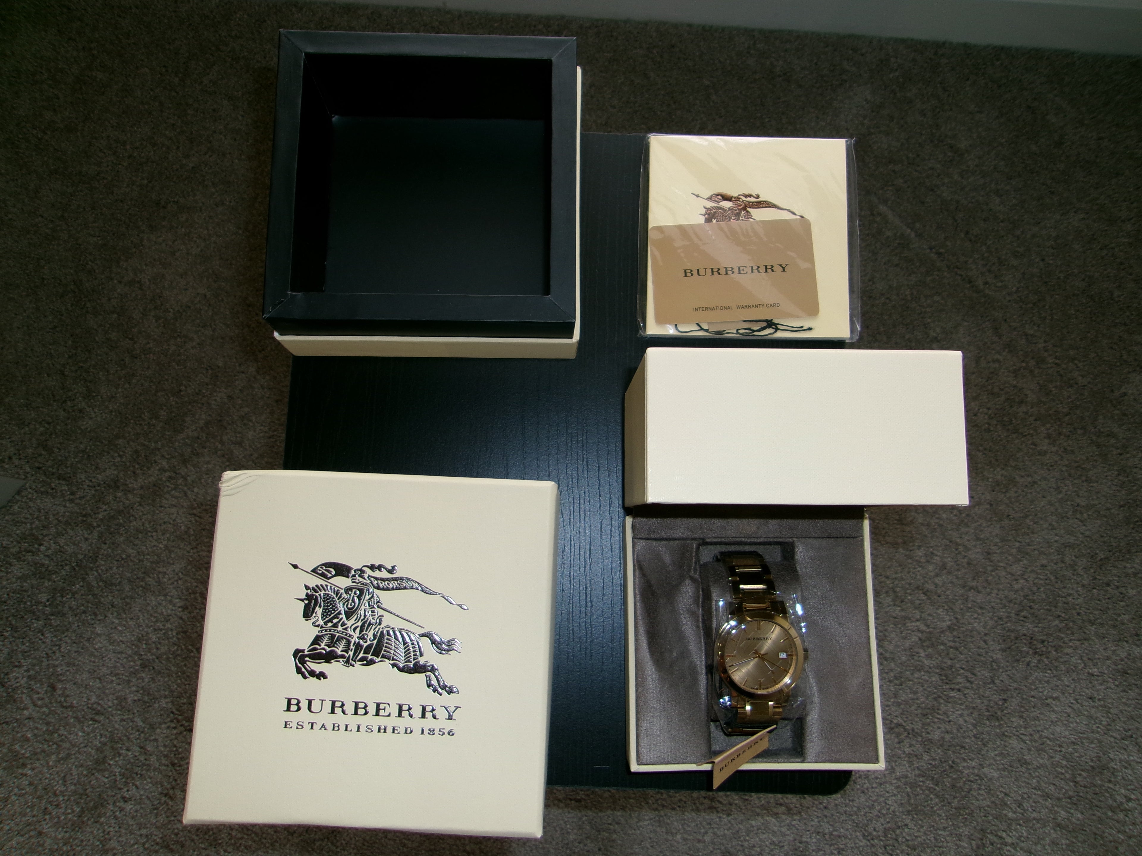 Burberry watch in an open box with branded packaging on a dark surface