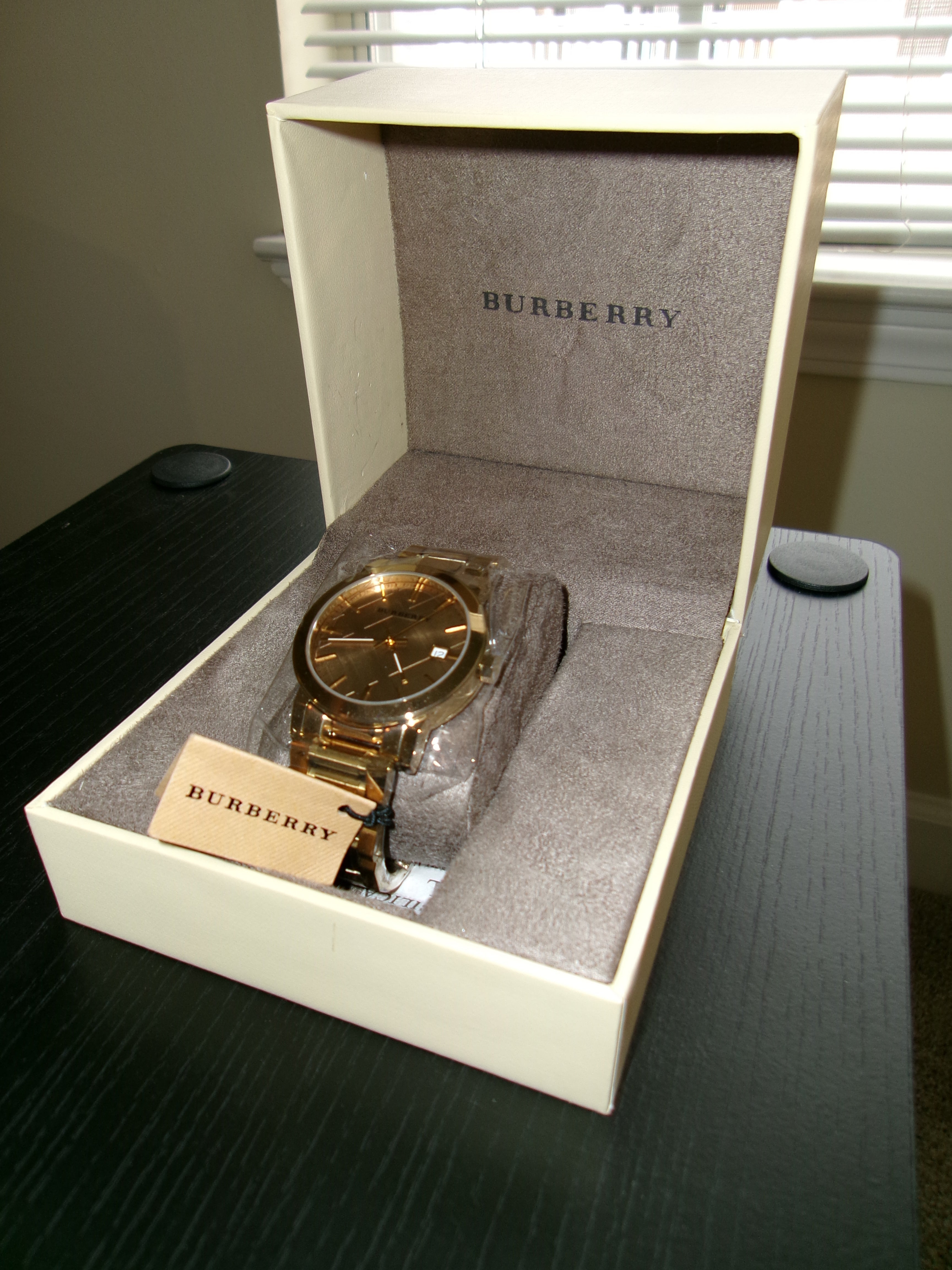 Gold watch in a Burberry box on a dark surface