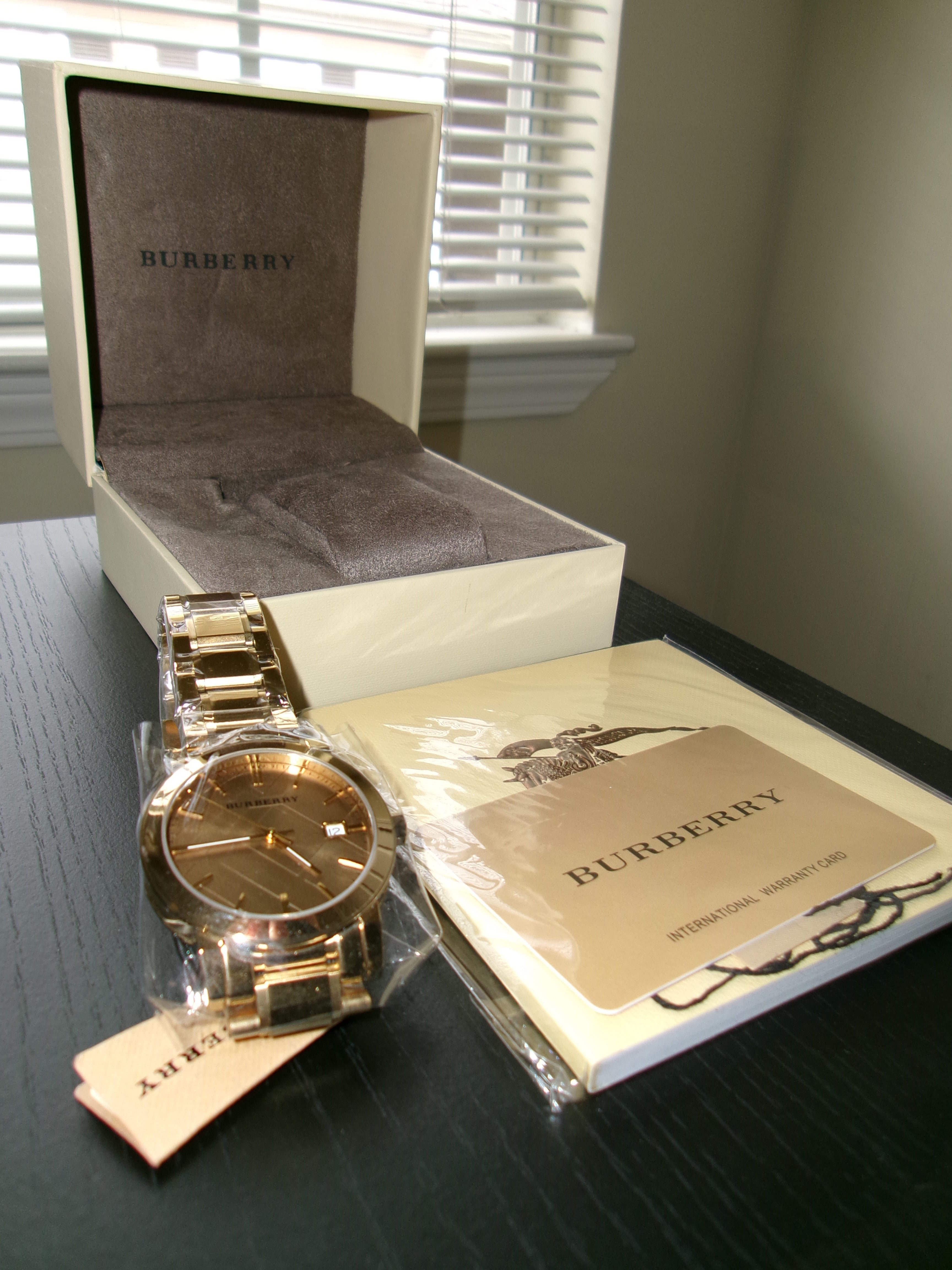 Gold Burberry watch on a branded box with a blurred background