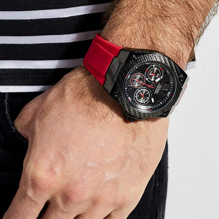 Black watch with red strap on a person's wrist.