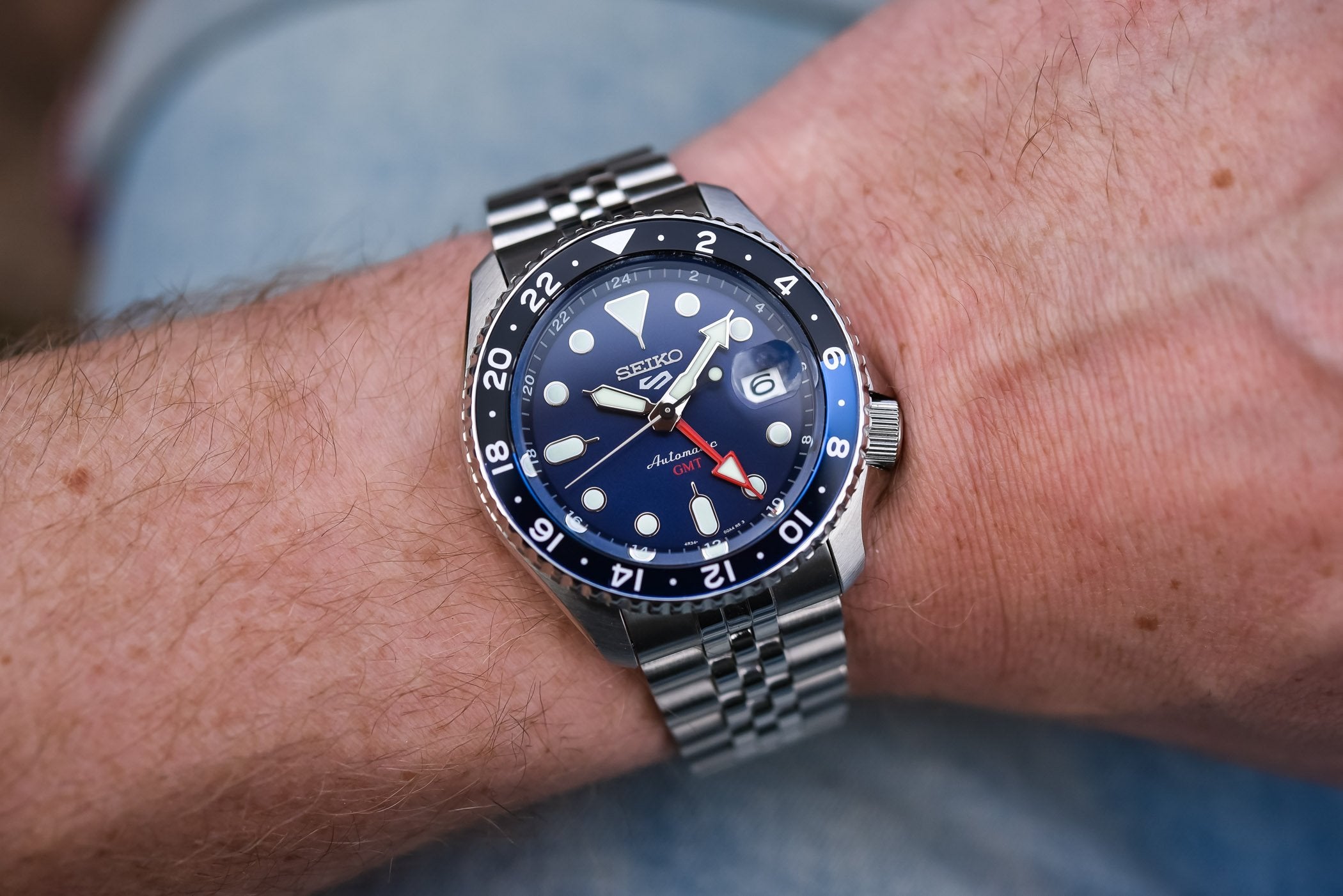 Close-up of a wrist wearing a Seiko watch with a blue face and silver bracelet.