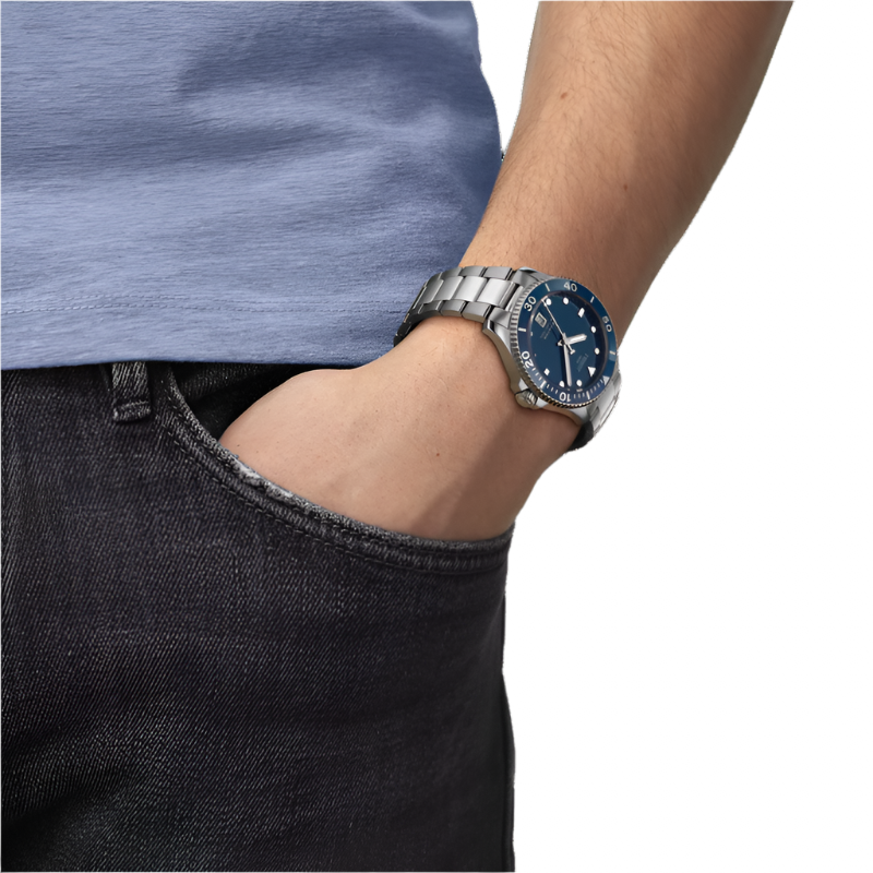 Person wearing a silver watch with a blue face on a plain background