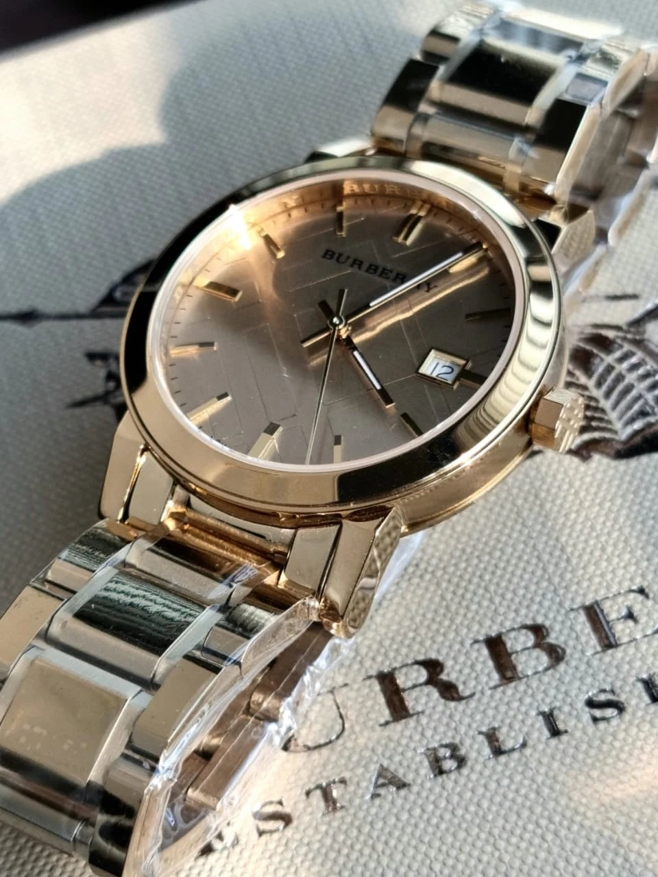 Close-up of a gold wristwatch on a textured surface.