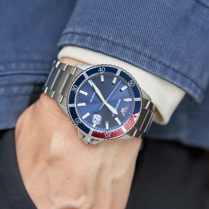 Close-up of a wristwatch with a blue face and metal band on a person's wrist.